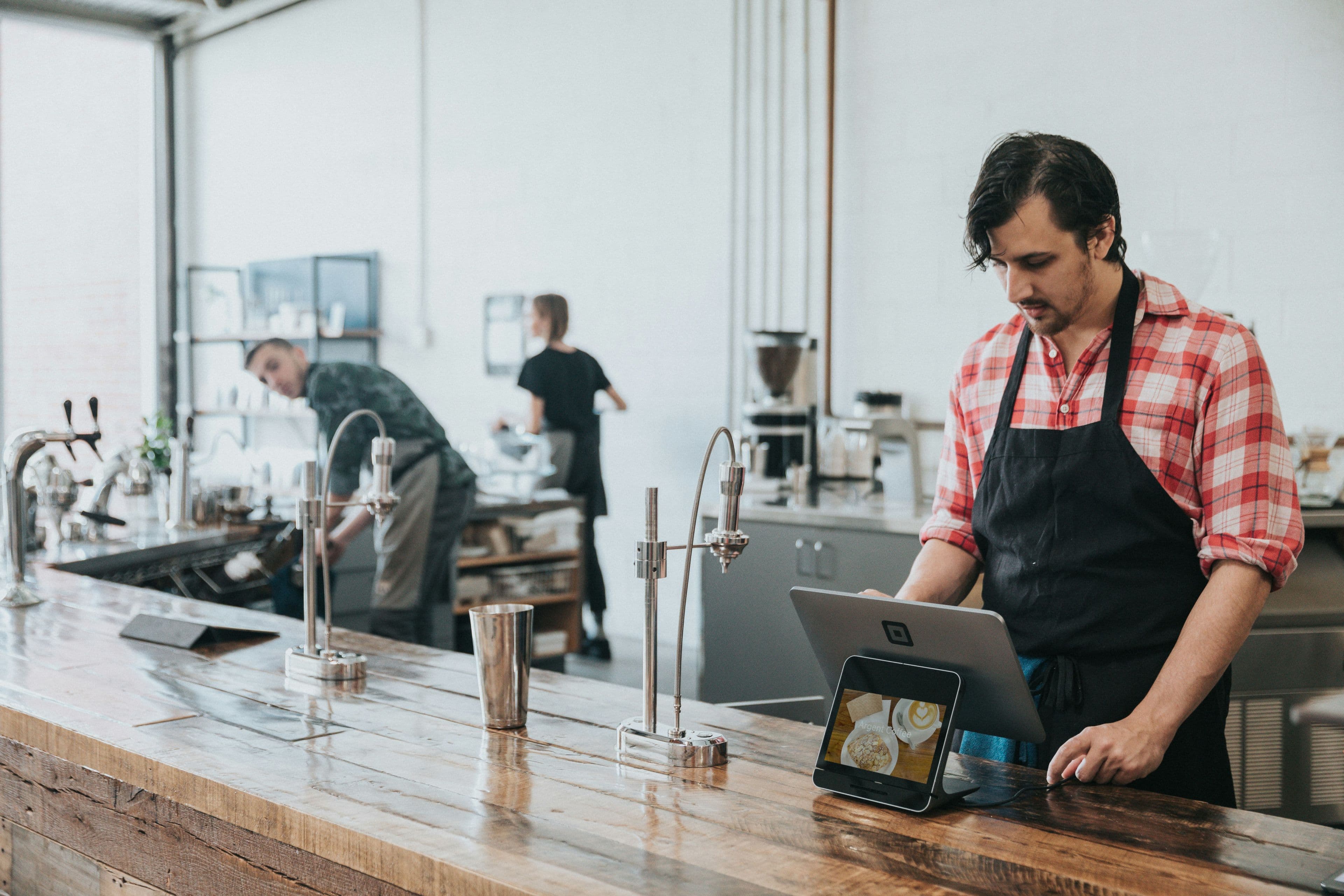 Barista registrando un pedido en la caja de una cafetería